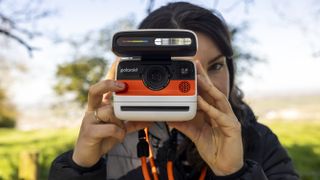 A female photographer holds the Polaroid Flip instant camera up to her face