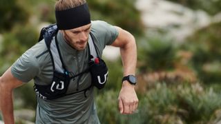 Man wearing Polar Grit X watch while running on a trail