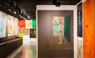 Gallery, colourful artwork on walls, white gloss floor, black ridge ceiling with black spotlights shining on artwork