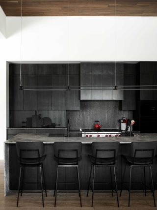 A black wooden kitchen with a red swath and dark grey countertops