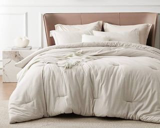 A Bedsure beige queen size comforter on bed in neutral bedroom with marble effect side table