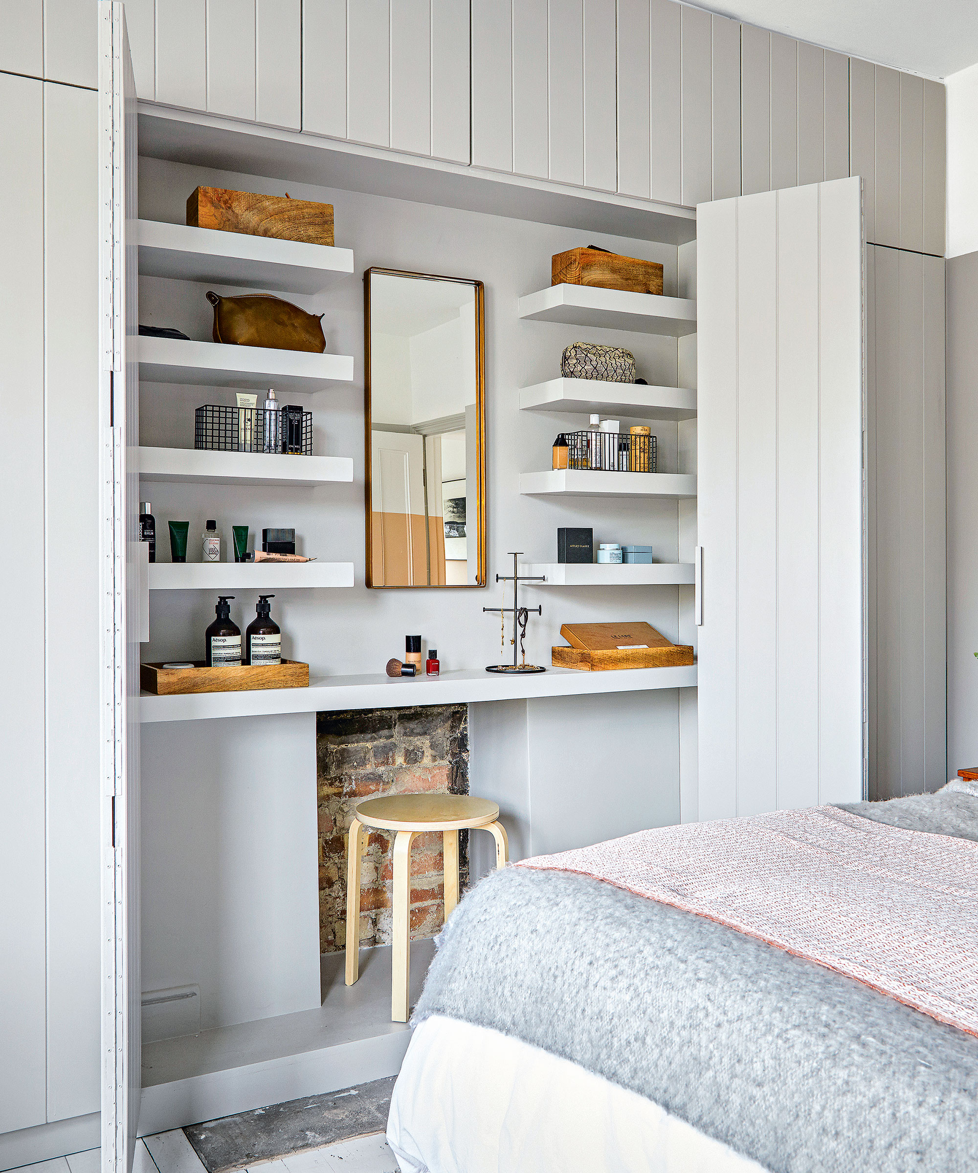 A main bedroom with built in shelving and a dressing area with a small wooden stool