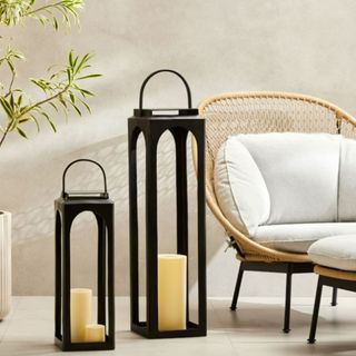 Tall black outdoor lanterns from West Elm next to a wicker lounge chair