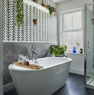 Bath tub on concrete effect floor with monochrome wallpaper