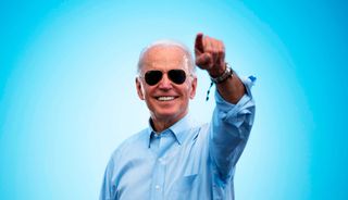 Photo of Joe Biden wearing sunglasses with a sunburst effect on a blue background behind his head.