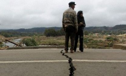 Residents walk over a highway in Chile cracked by the quake.