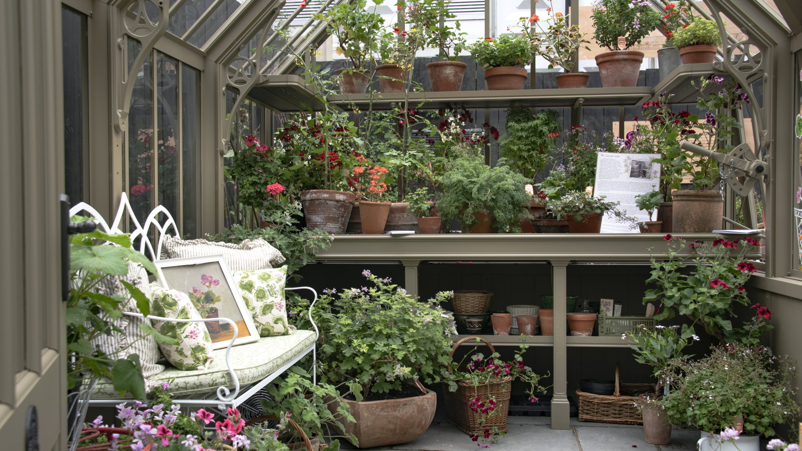 A rustic greenhouse filled with potted plants and a metal bench