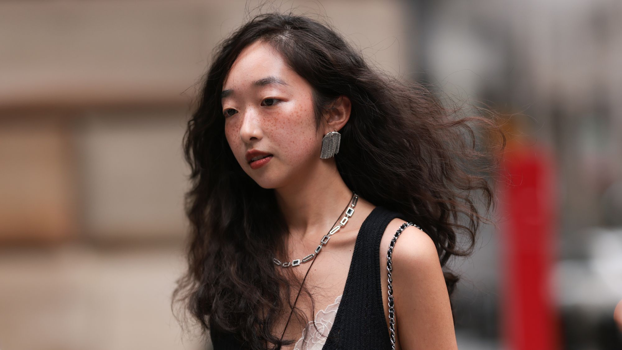 a woman with flowy wavy hair walking down the street with her freckles on show wearing watercolour blush