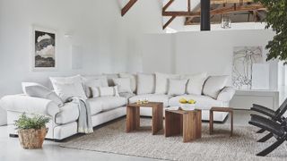 Living room with white sectional sofa with pillow back and ceiling open to rafters