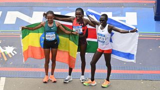 Three Pro Women's Open Division winners pose on the New York Marathon finish line with national flags.