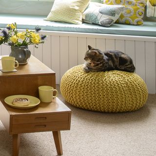 cat on pouffe and flower in vase