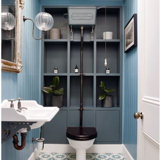 Cloakroom with dark blue walls, tiled floor, white basin and toilet.