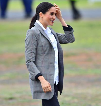 Meghan Markle wearing a gray blazer and black jeans in 2018