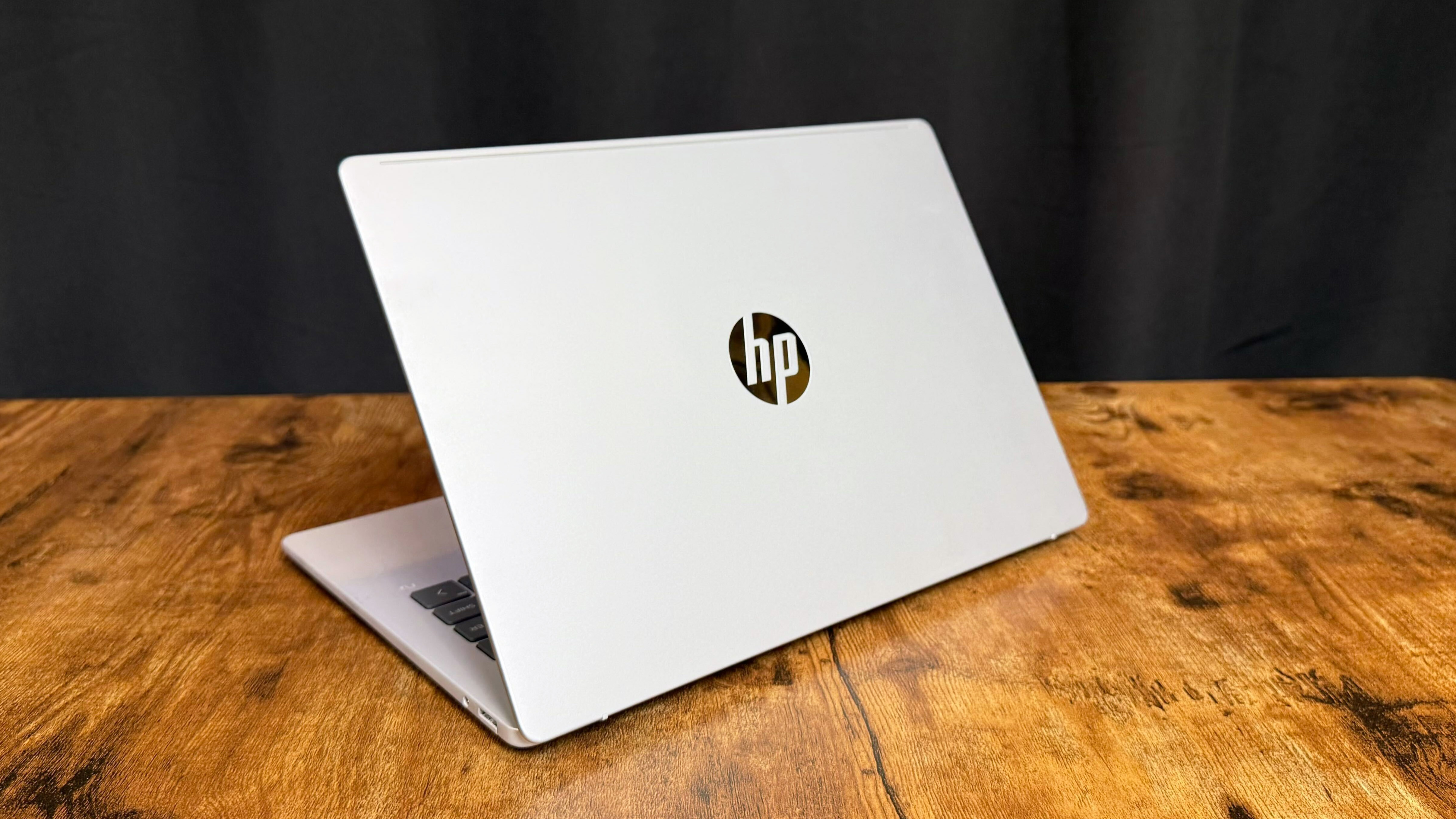 HP OmniBook 5 14 AI PC on a wooden table against a black backdrop.