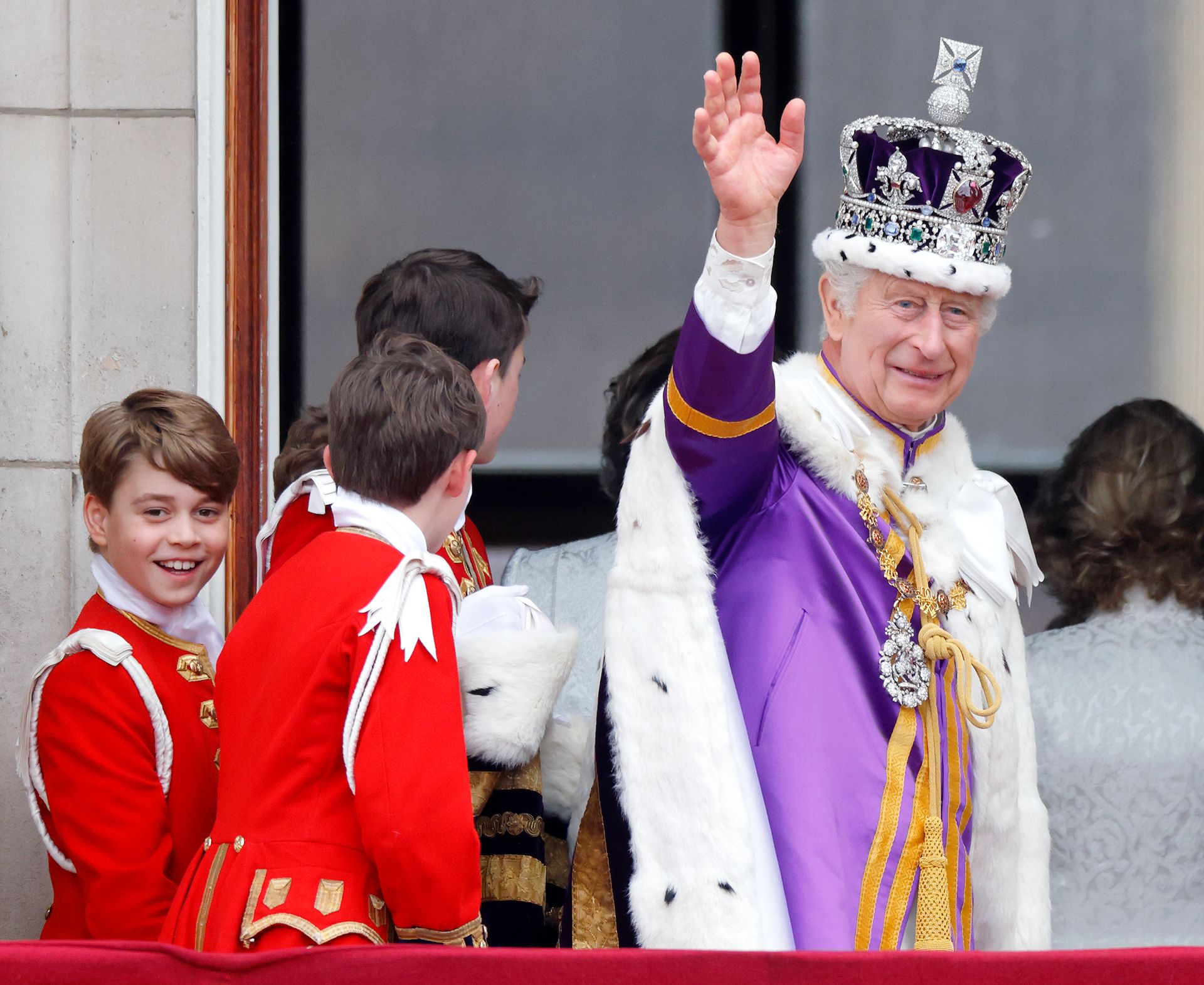 King Charles waving in his coronation robes next to Prince George