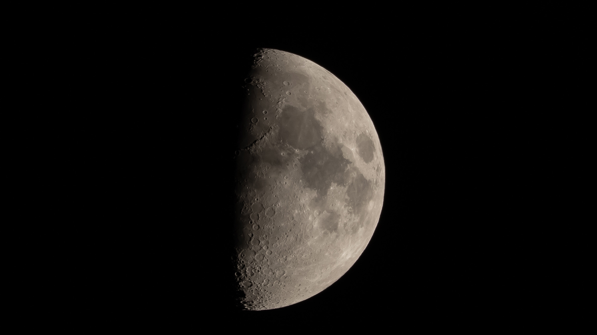 A waxing gibbous moon is seen in the night sky, with craters and dark lunar plains visible on its illuminated surface.