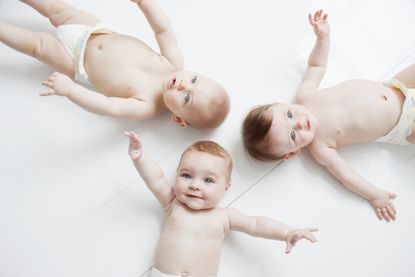 Smiling babies laying on floor waiting for baby gender predictor tests.