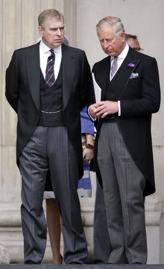 Prince Andrew and King Charles wearing suits and talking while looking serious