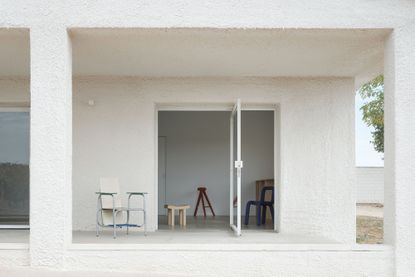 Casa Primitiva, an all white house in spain, seen among greenery and dusk skies