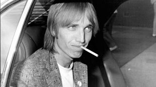 Tom Petty smoking a cigarette in the back of a car in 1980