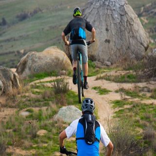 Two people riding mountain bikes along a gravel track