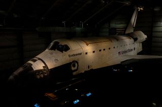 a space shuttle orbiter sits in a darkened hangar