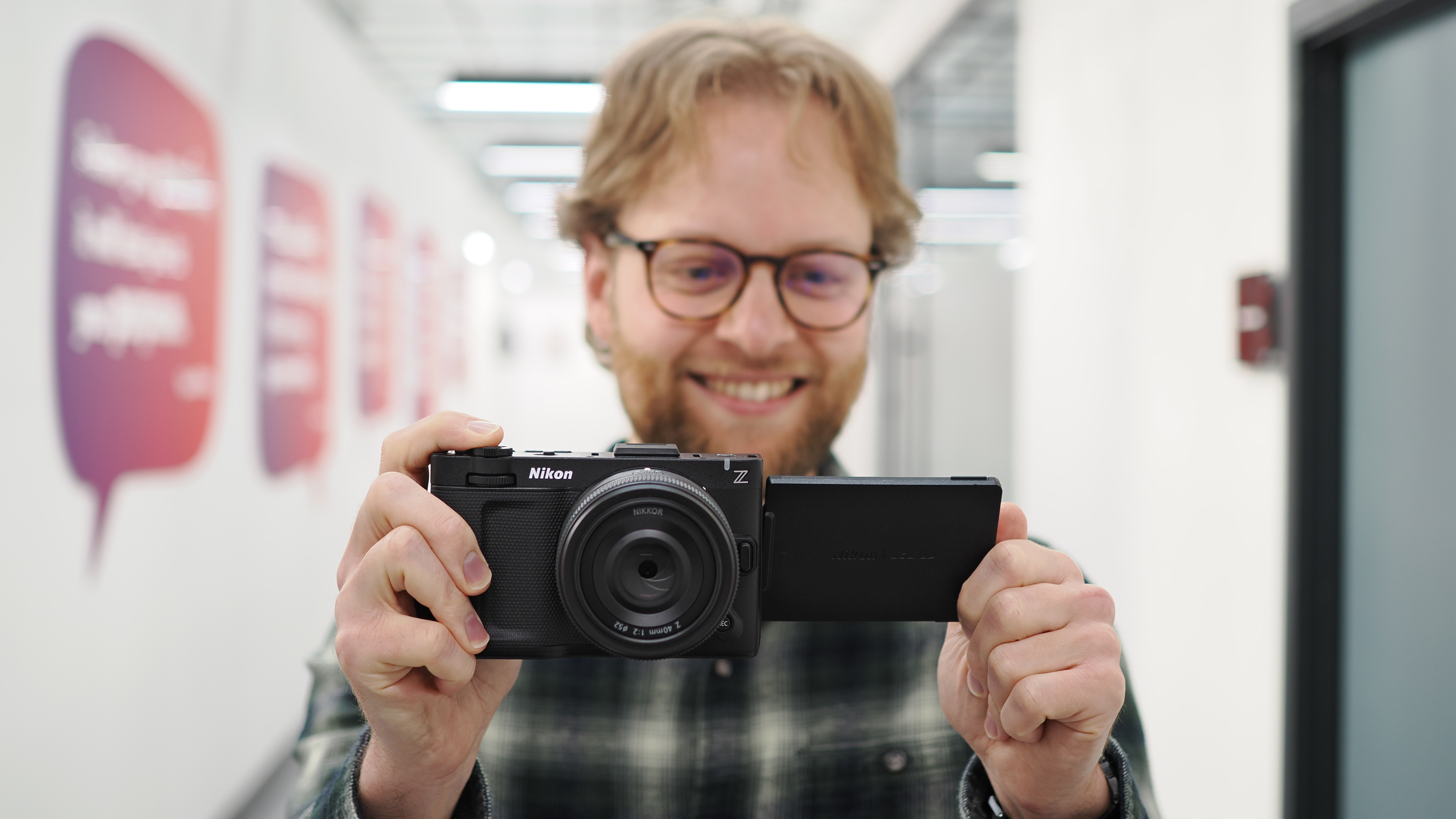 Mike Harris holding a Nikon ZR with 40mm lens in an office building