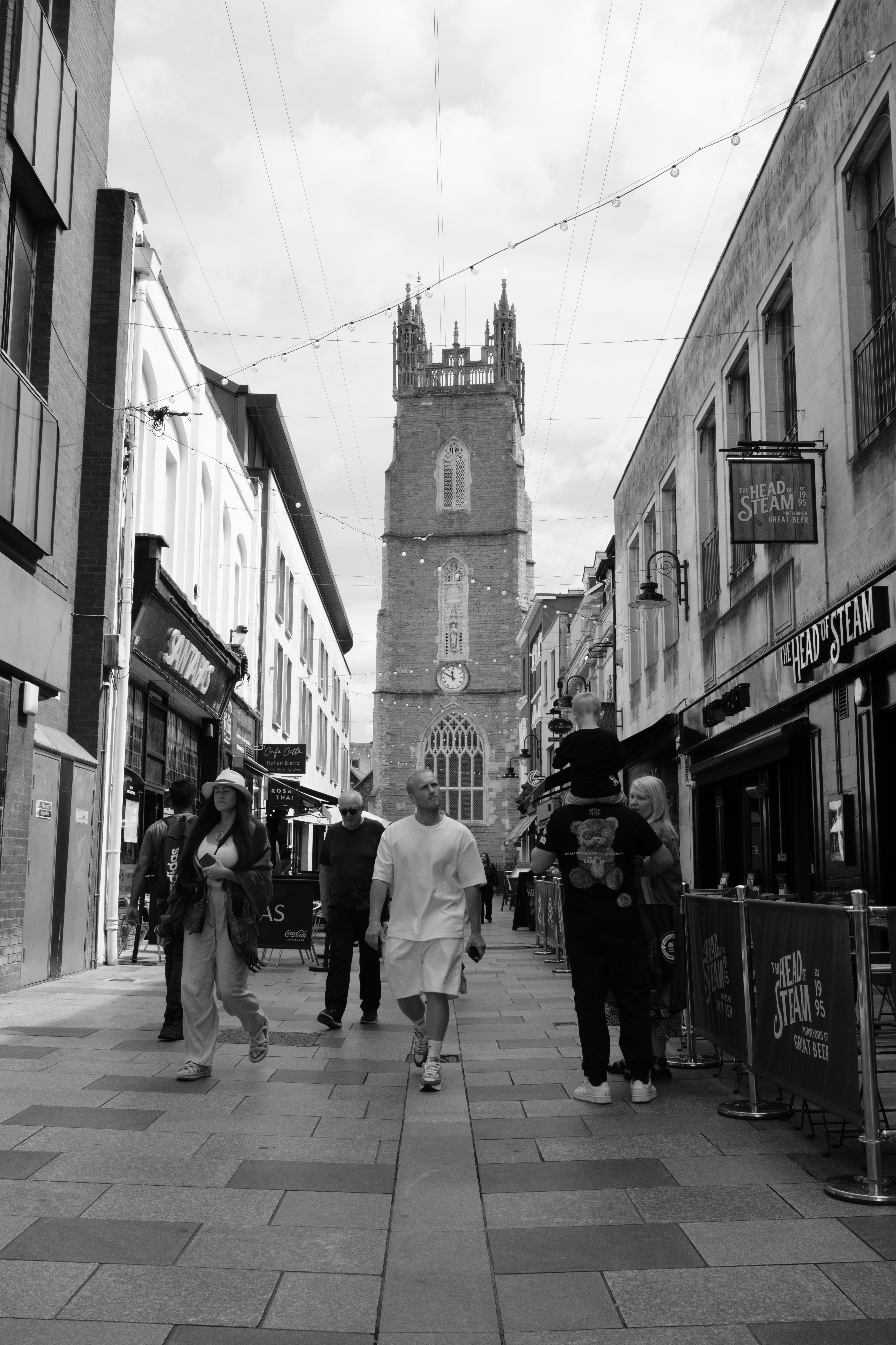 A street scene showing a couple walking down a street with a church in the background, taken on the Fujifilm X-E5.