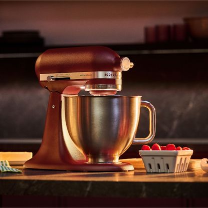 KitchenAid stand mixer in red on wooden worktop with light on, bedside raspberries