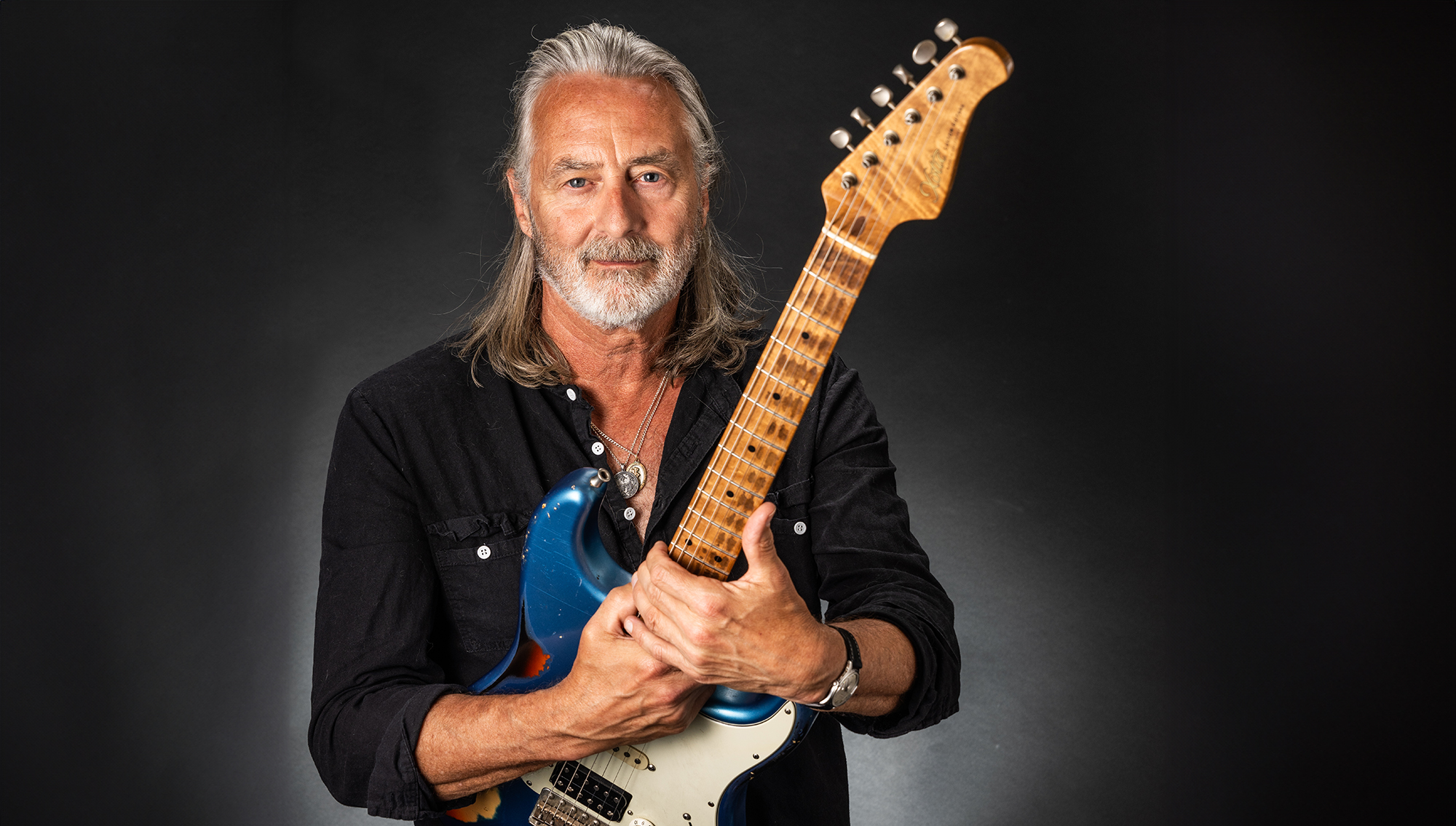 A photo of Allen Hinds holding his signature Xotic California Classic XSC-AH electric guitar against a black background