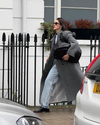 Fashion influencer Valeria in London wearing a chic fall outfit with faded jeans, a long herringbone wool coat, and The Row's Margaux 17 bag.