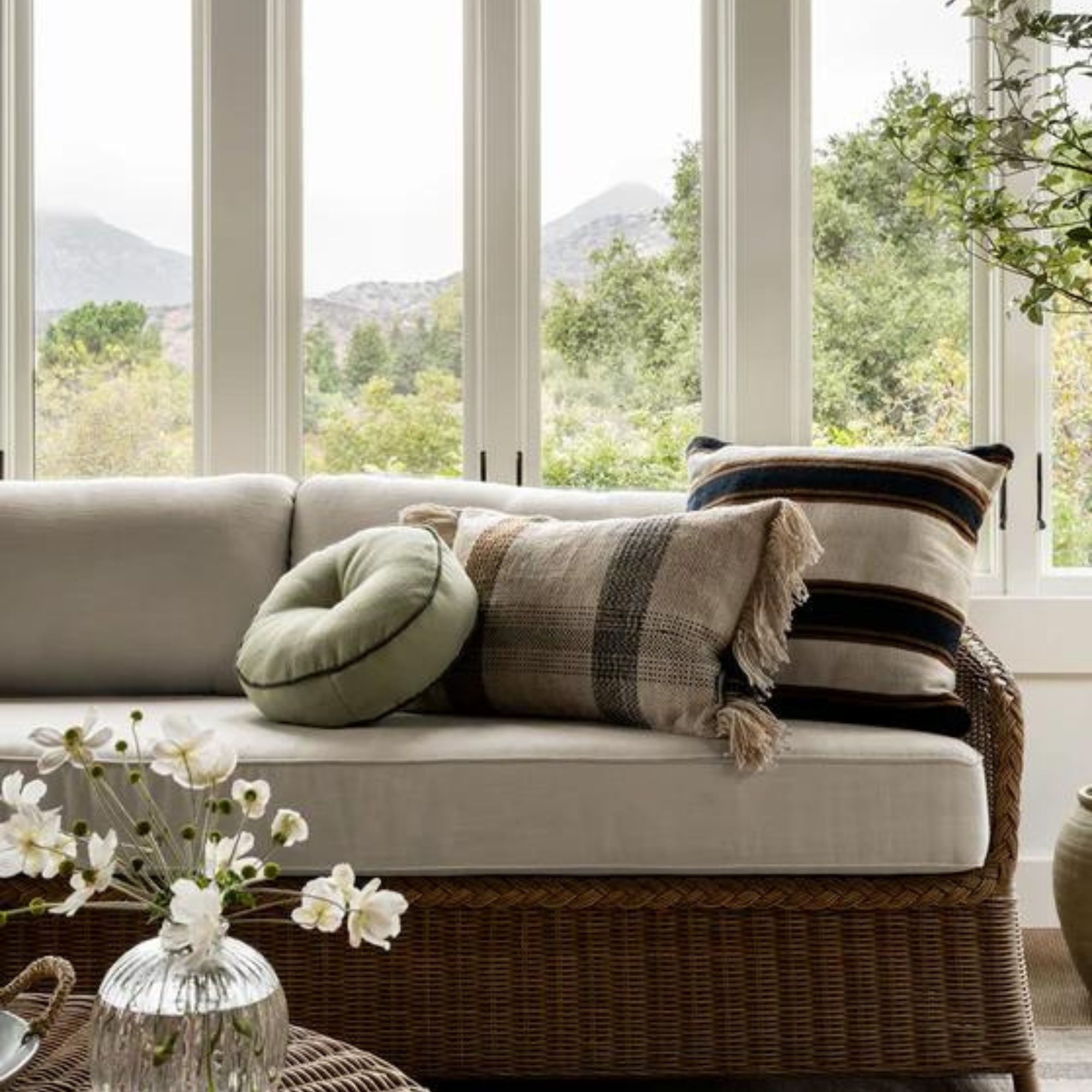 A selection of throw pillows on a wicker sofa
