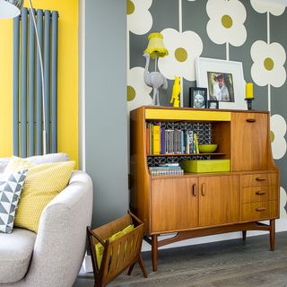 Open plan living space decorated in grey and yellow with retro style wallpaper