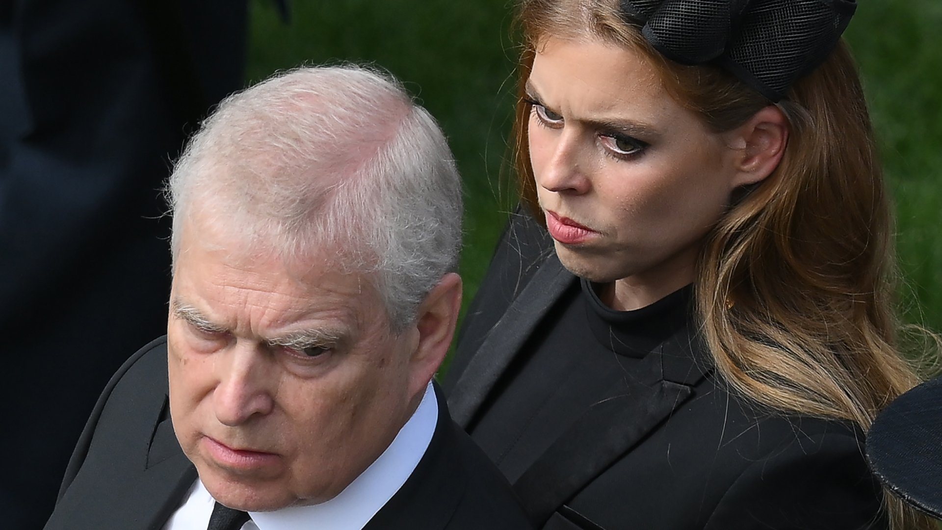 Prince Andrew looks stern wearing a suit and Princess Beatrice wears a black dress