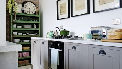 Dark green shaker kitchen with grained cupboards and pink walls.