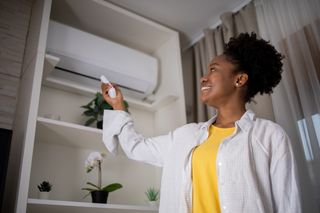 Woman turning on air conditioner with remote