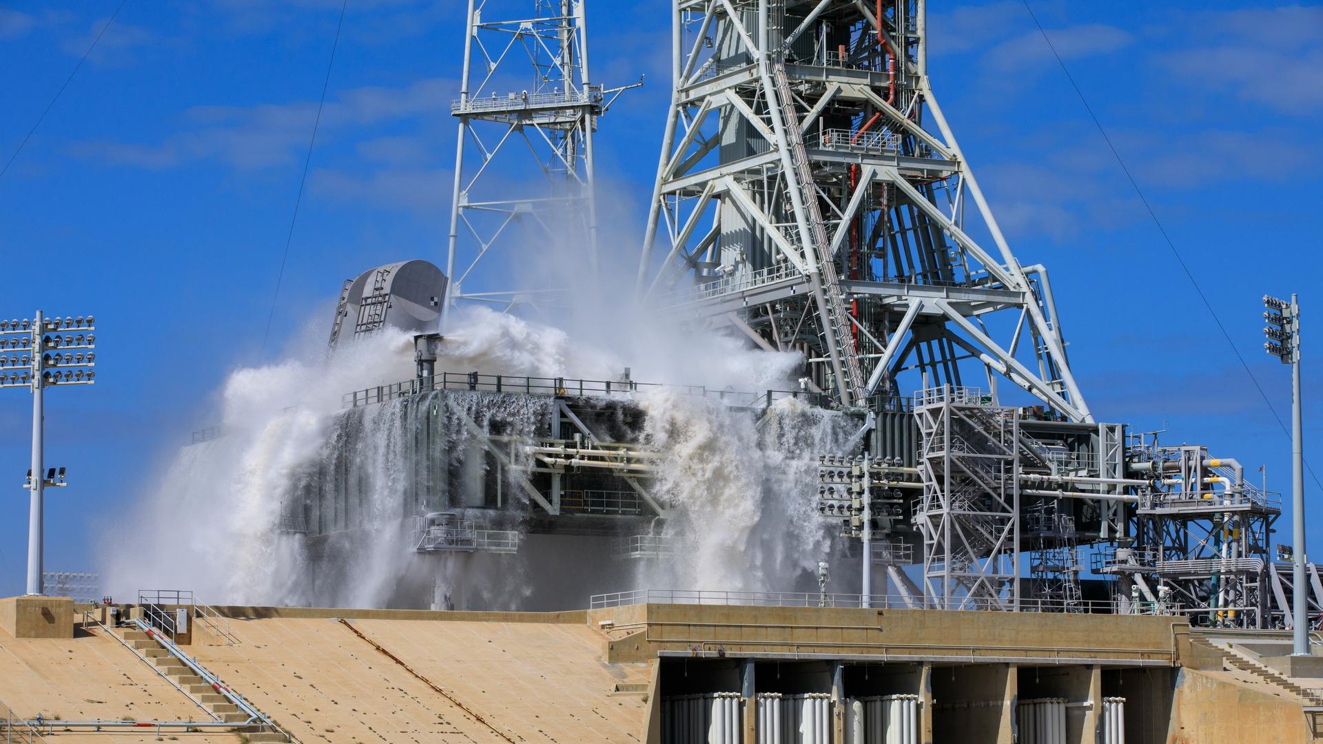 water splashes and froths at the base of a large metal tower