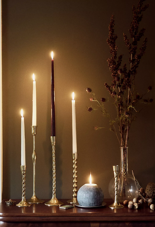 gold twisted candlesticks on a table with neutral tapered candles and dried flowers