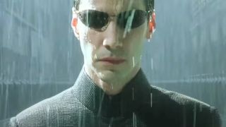 Keanu Reeves stands with a grim face in a rainstorm in The Matrix Revolutions.