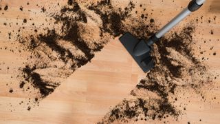 A vacuum cleaner being used to pick up dirt on hardwood floors
