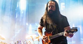 Against a backdrop of celestial stage lights, John Petrucci plays a riff on his signature Ernie Ball Music Man JP15 7-string