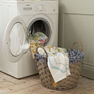 White washing machine next to a laundry basket of clothes