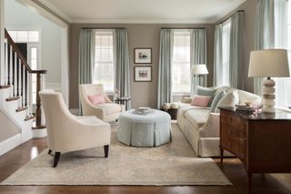 A beige and pale blue living room design with floor length drapes.
