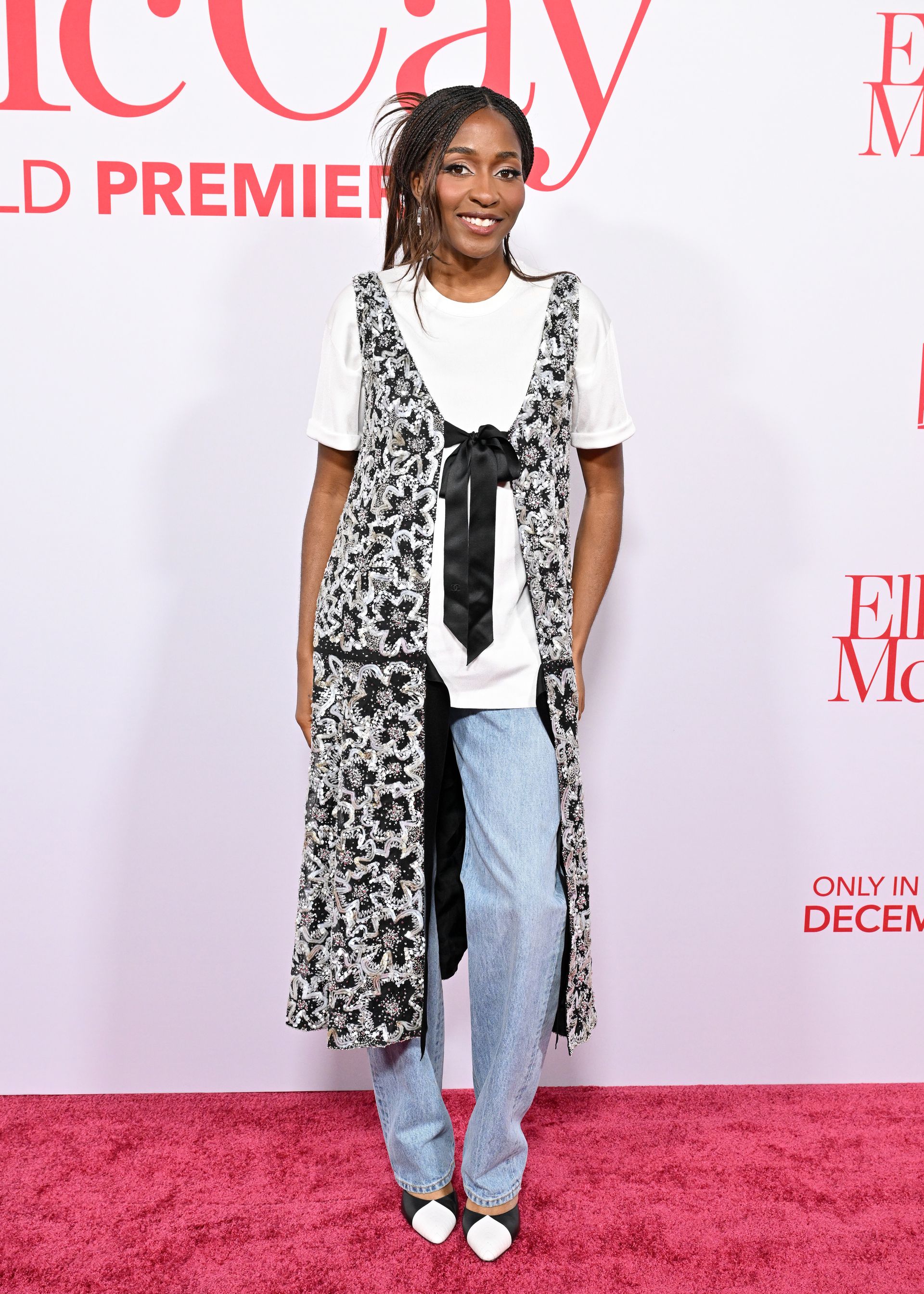 Ayo wears a white tee, black and white top, light-wash jeans, and black and white pumps.
