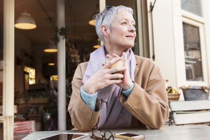 Senior woman having a coffee outside a coffee shop.