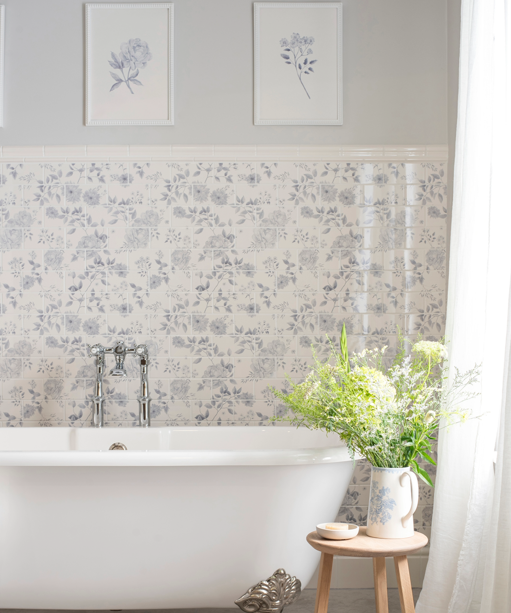 Blue bathroom idea with half blue tiling and half pastel blue painted wall above freestanding bathtub and stool with flowers