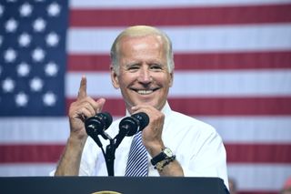 Joe Biden gestures in front of an American flag