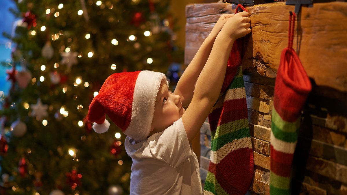 Child hanging his stocking up by the fireplace