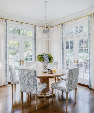 light and bright dining room with round table and white and blue drapes