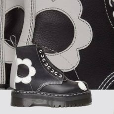 A pair of black Dr. Martens boots embroidered with white flowers.